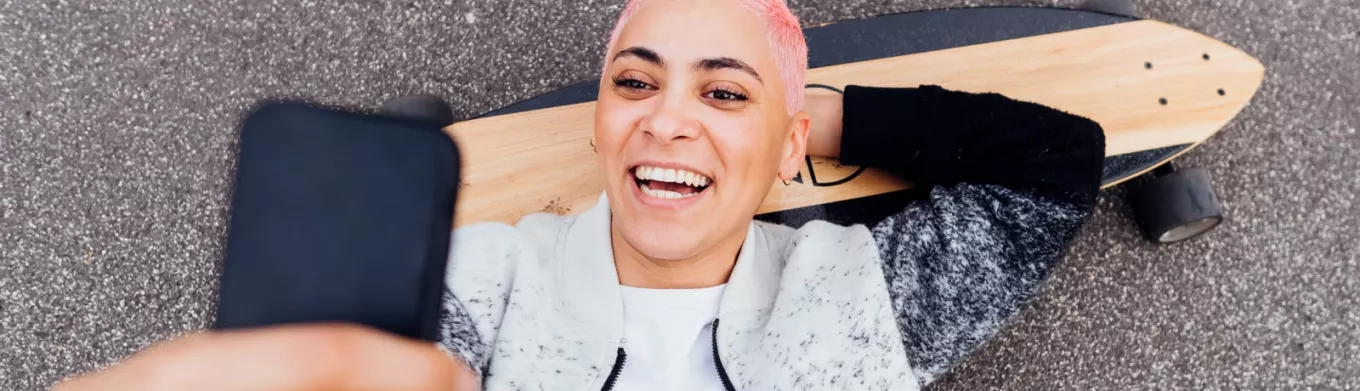 Jeune fille sur son skateboard regardant son smartphone 