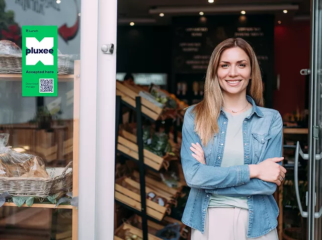 Commerçant devant son magasin avec le sticker Pluxee sur la vitrine