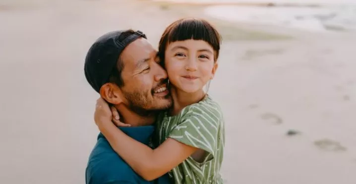 Dad carrying his daughter on the beach 
