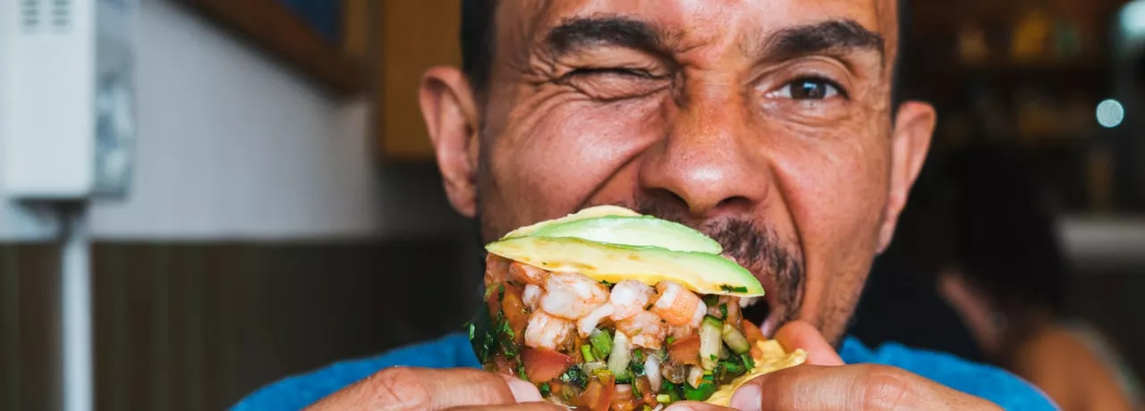 Homme mangeant un tacos aux crevettes