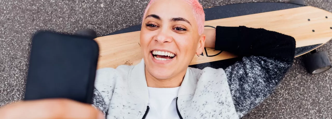 Jeune fille sur son skateboard regardant son smartphone