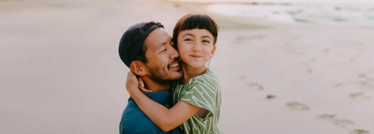 Dad carrying his daughter on the beach 
