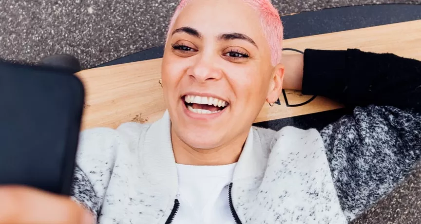 Jeune fille sur son skateboard regardant son smartphone