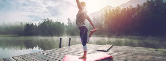 Woman doing yoga in front of a lake