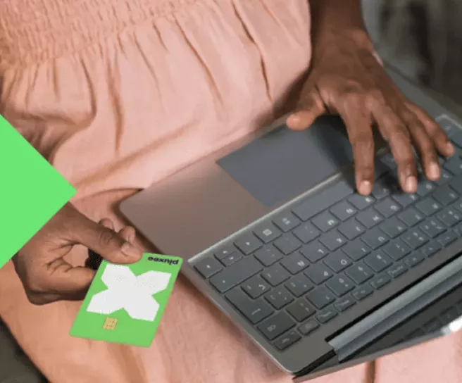 Girl in pink dress using her pluxee card on a laptop
